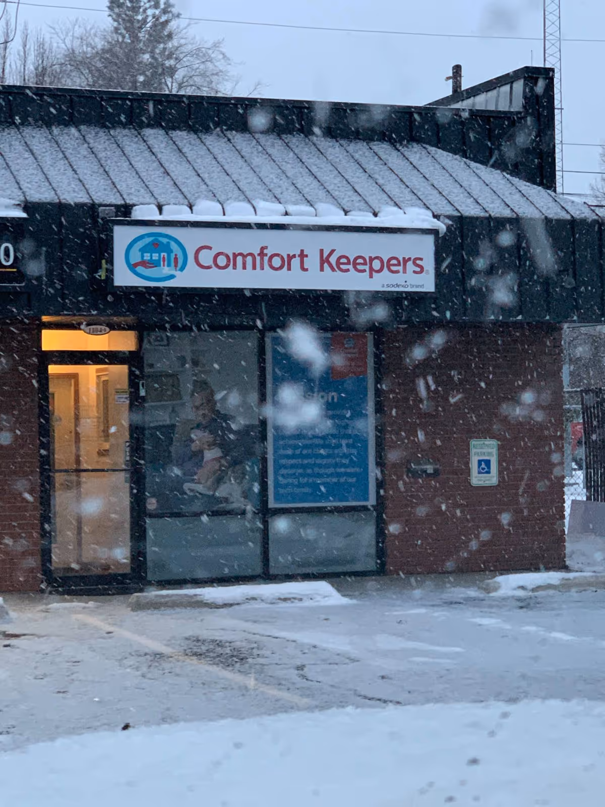 Snowy exterior of Comfort Keepers storefront with glass entry door.