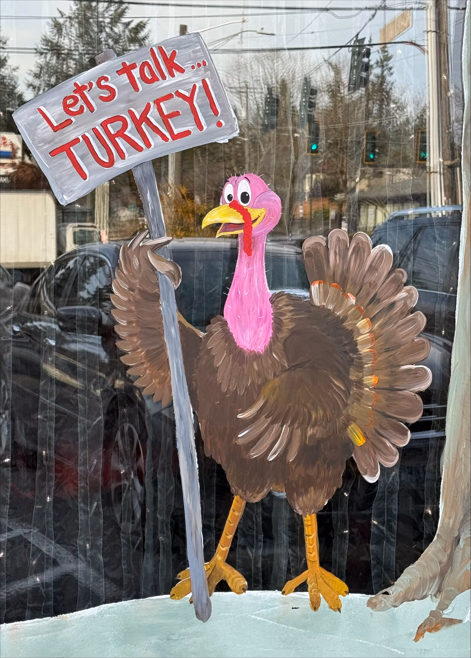 A painted turkey with a sign 'Let's talk TURKEY!' displayed in a storefront window.
