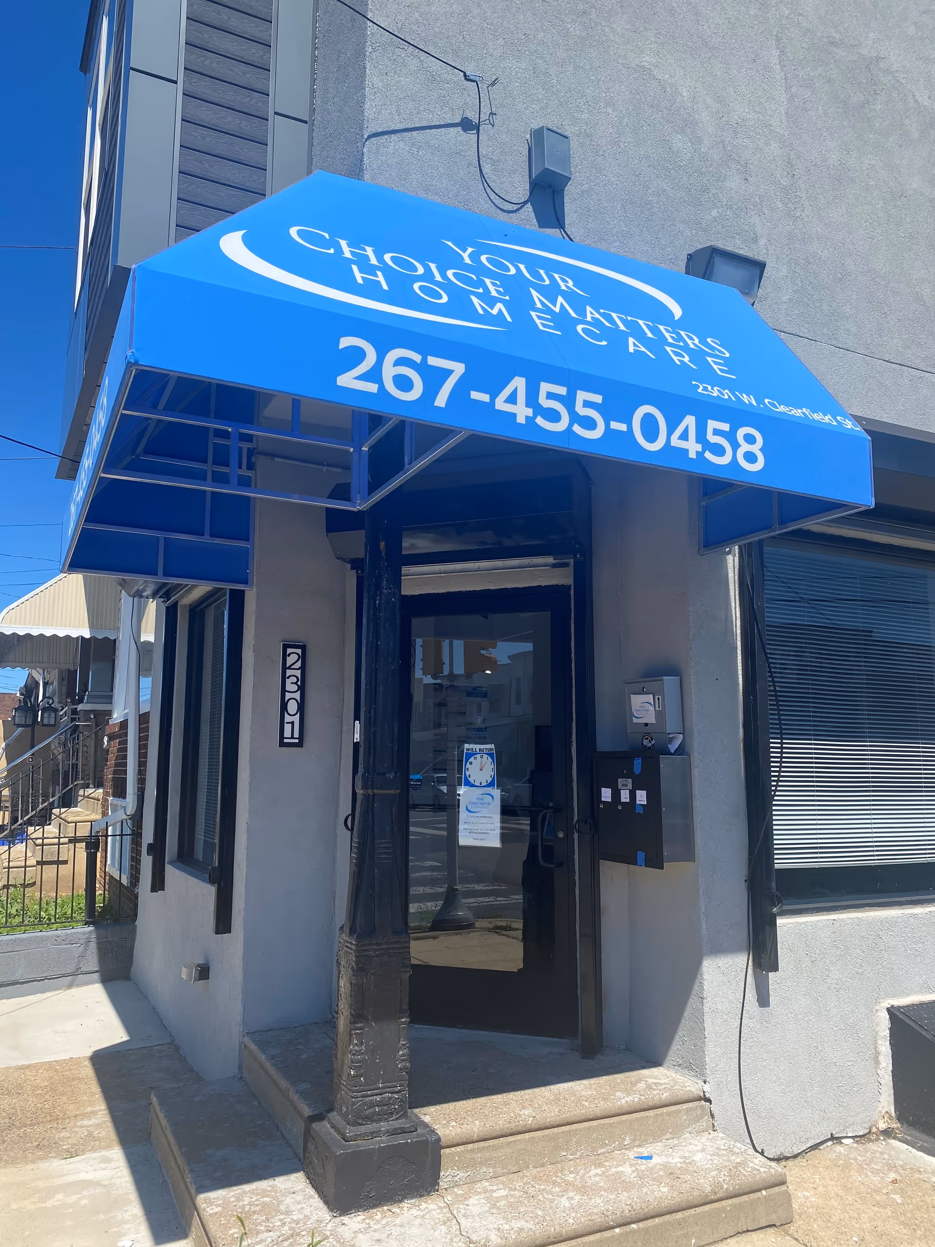 Blue awning displaying Your Choice Matters Homecare above a glass entrance door