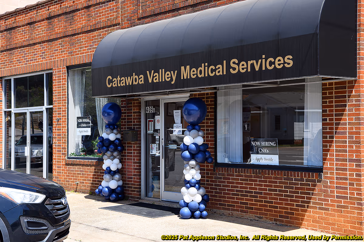 Brick storefront with black awning bearing Catawba Valley Medical Services and balloon decorations.