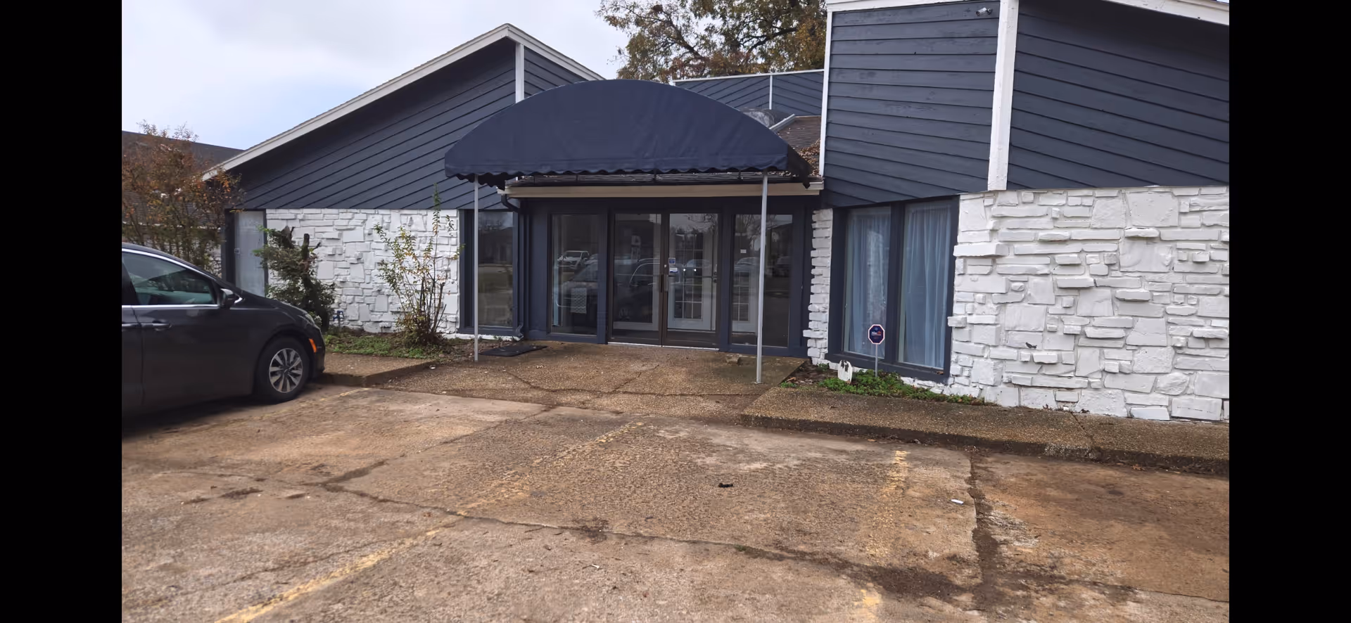 Front exterior of Mercy Springs Living Center with glass doors and a blue awning.