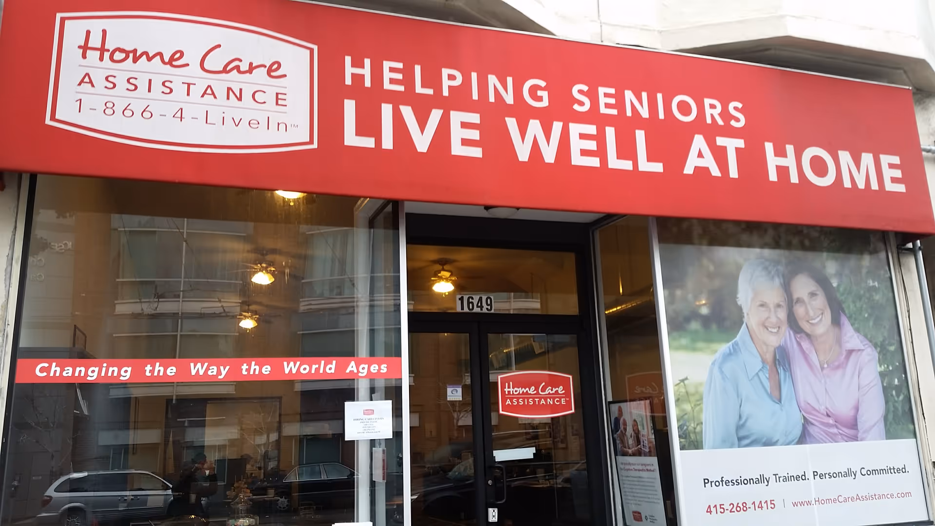 Red storefront awning reading 'Helping Seniors Live Well at Home' above glass doors.