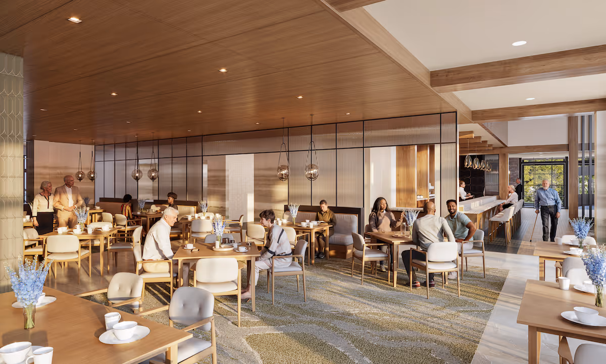 Spacious, warm dining room with seniors seated at tables and a bar area, wood ceilings, pendant lights and floral centerpieces.
