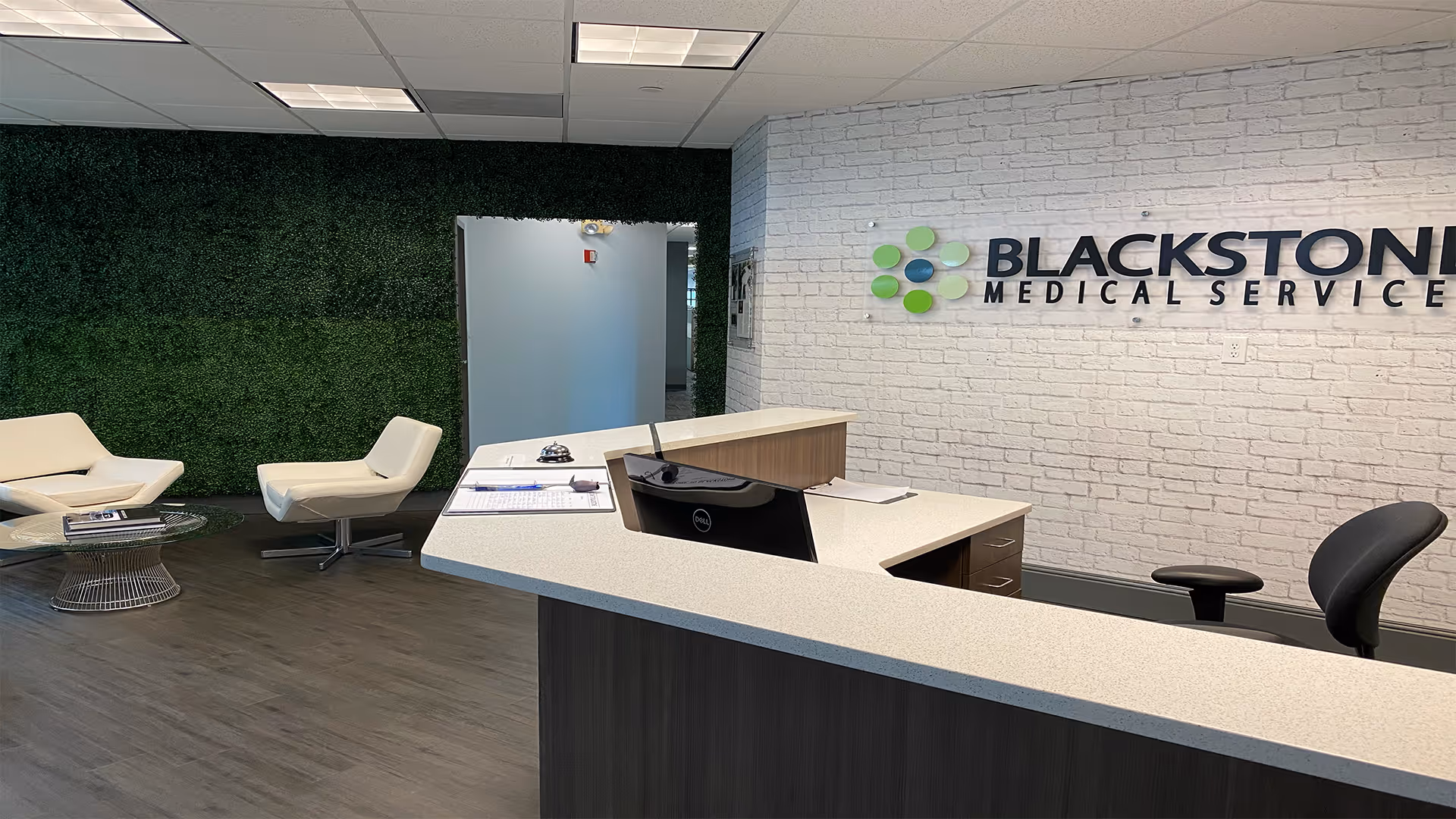 Reception desk in a modern facility lobby with white brick wall and green accent wall.