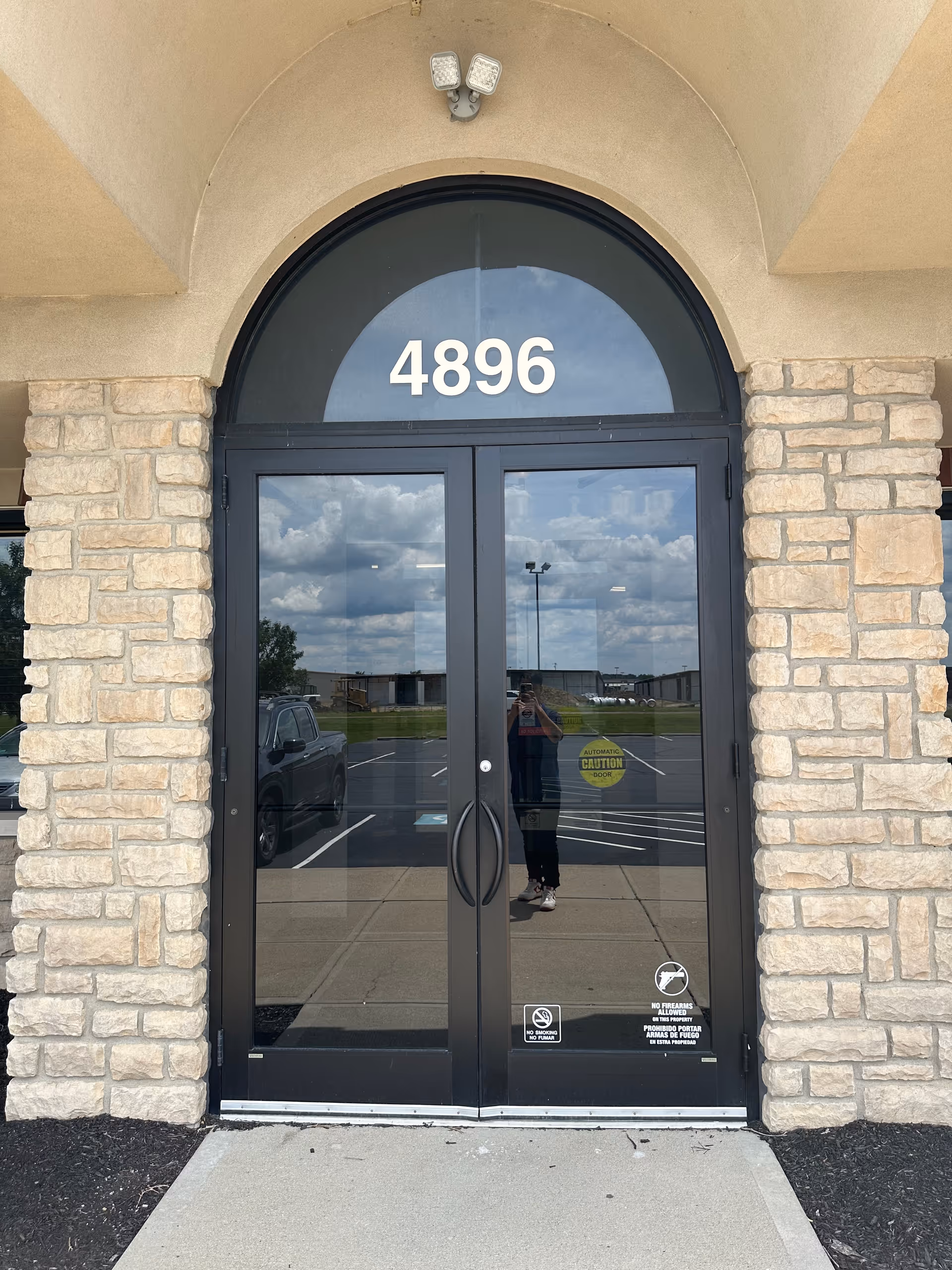 Double glass doors with the number 4896 set in an arched window under a stone facade.