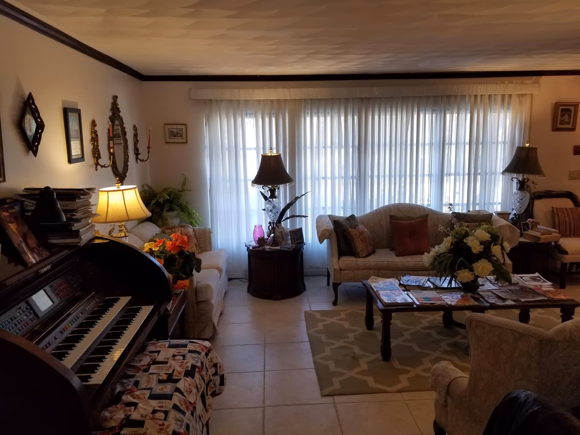 Cozy living room with sofas, lamps, a coffee table, and sheer-curtained windows.
