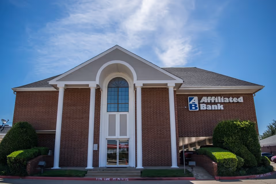 Brick building with arched entrance and Affiliated Bank sign against a blue sky.