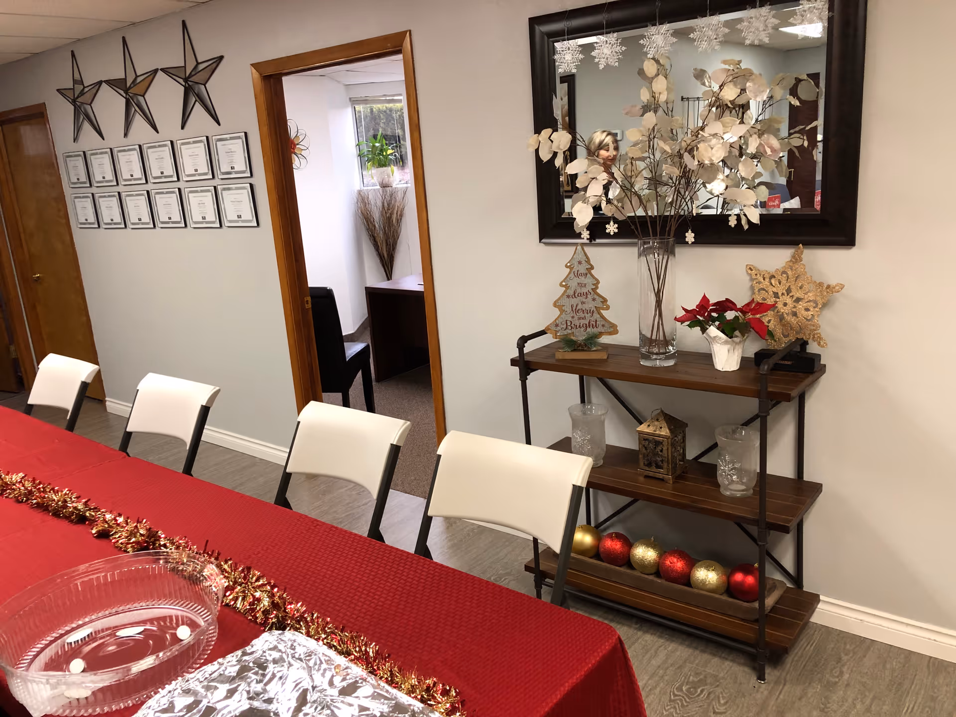 Red-draped dining table with white chairs and holiday decorations in a senior care facility.