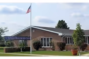 Brick Gilman Healthcare Center building with flagpole and manicured lawn.