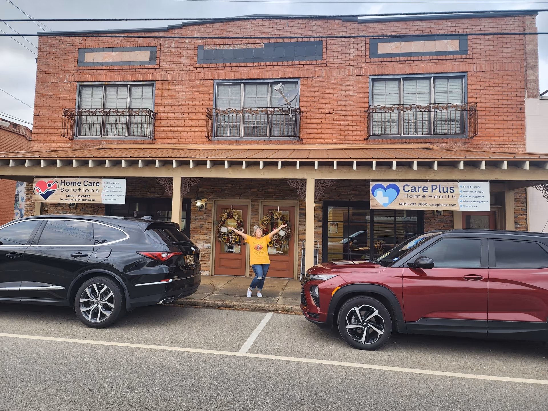 Brick storefront with two care signs, a person in yellow at the door, SUVs parked outside.