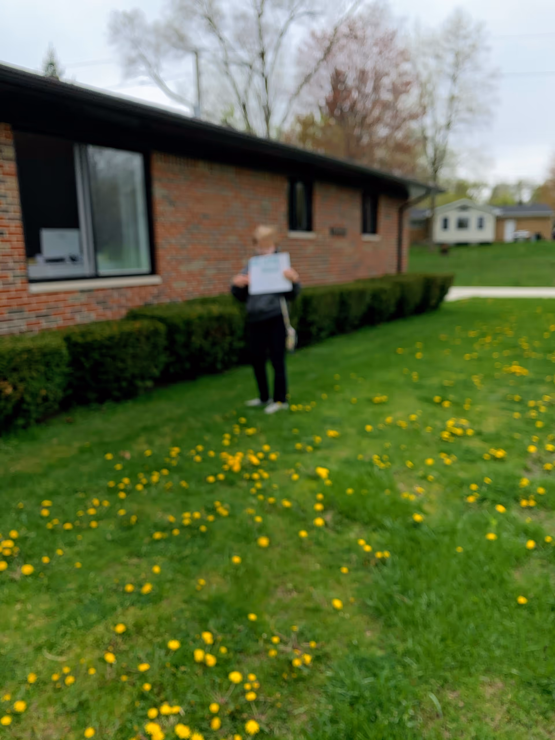 A person stands on a grassy lawn outside Orchard View Care Home holding a sign.