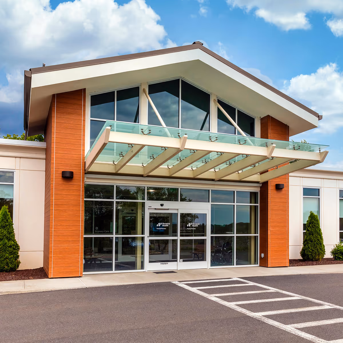 Modern senior living facility entrance with brick columns and glass canopy.