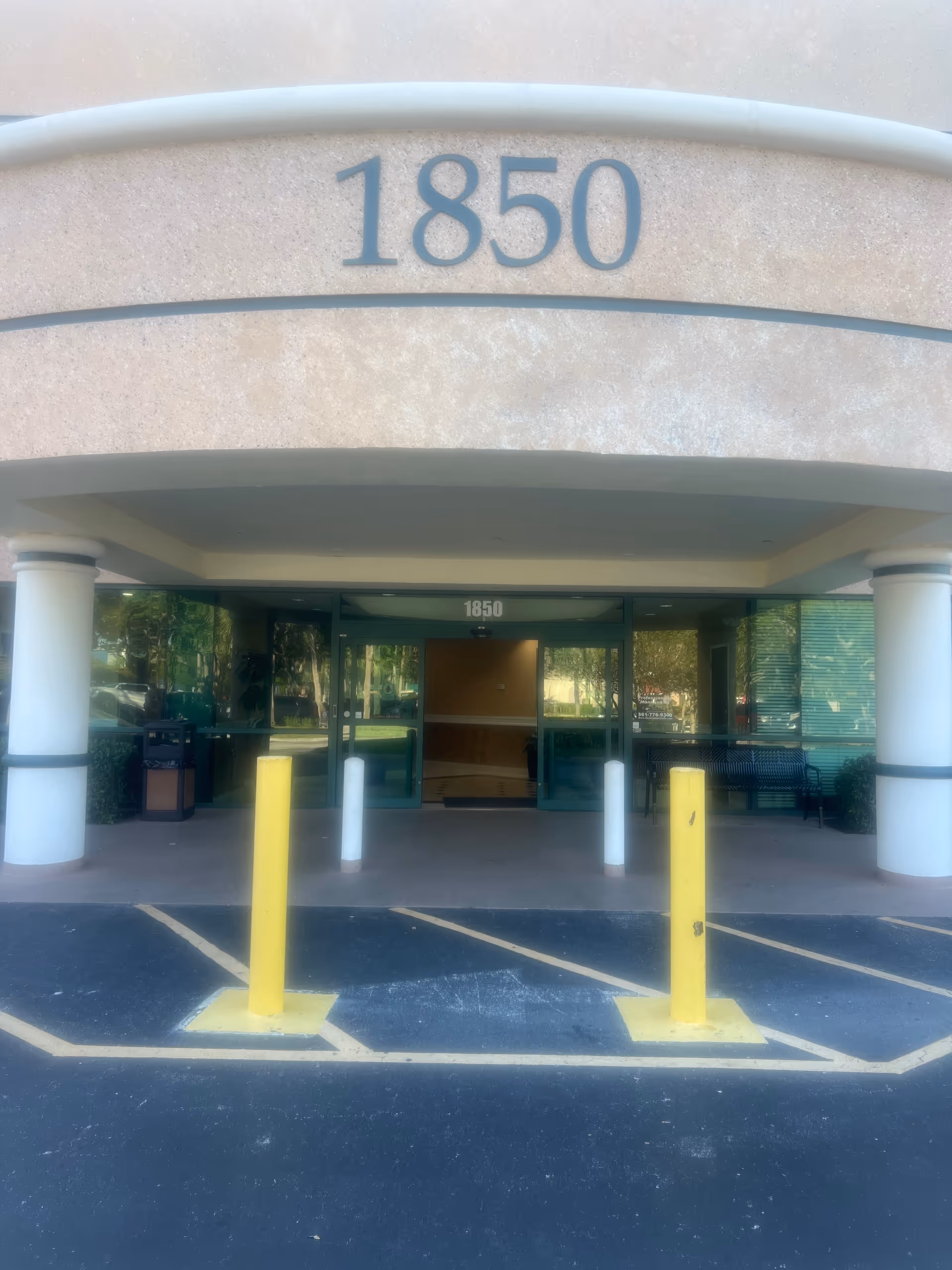 Entrance of a facility with 1850 above doors, glass lobby, and parking area.