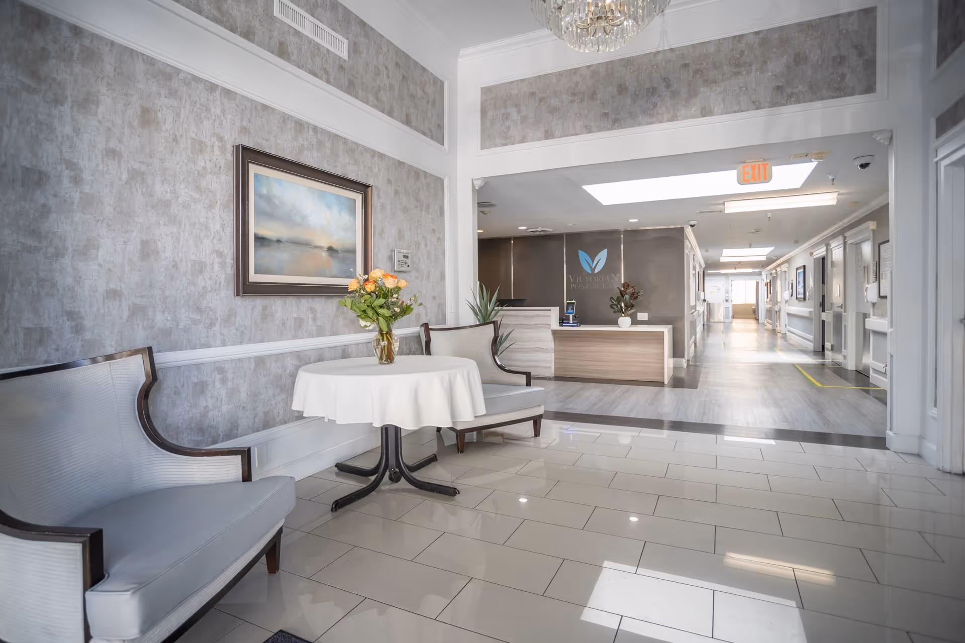 Bright lobby with a round table, flower centerpiece, and reception desk.