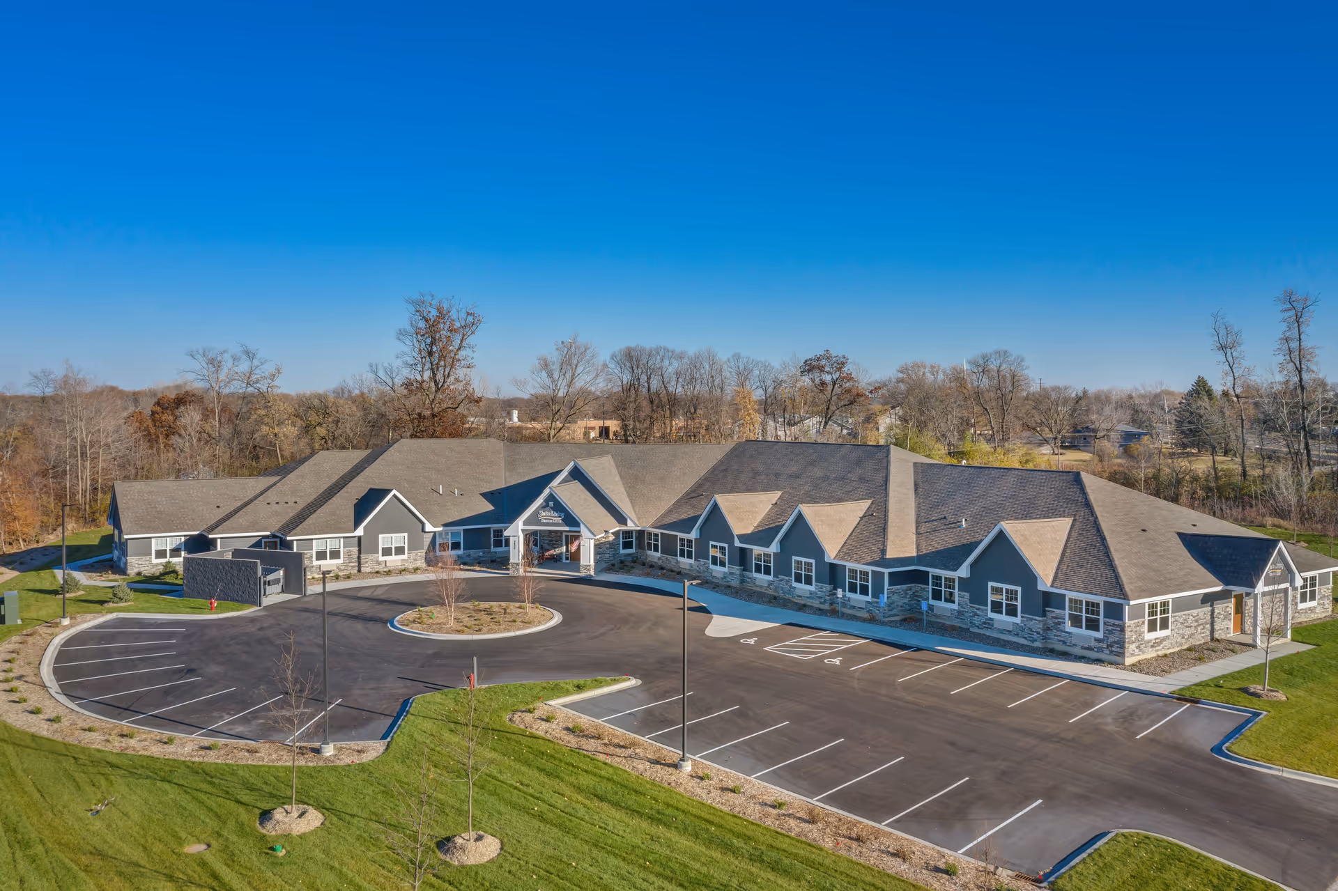 Exterior view of a senior living facility with a large parking lot and circular drive.