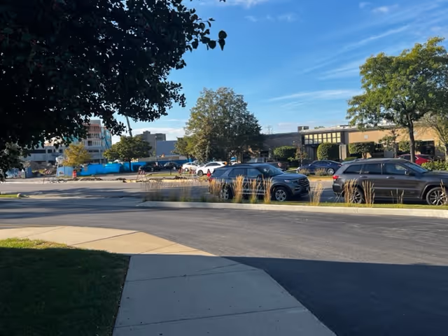 Exterior view of a senior home with cars in the parking lot and trees.