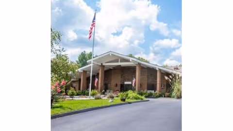 Front exterior of Signature Healthcare of Erin featuring flag, brick facade, and covered entrance.