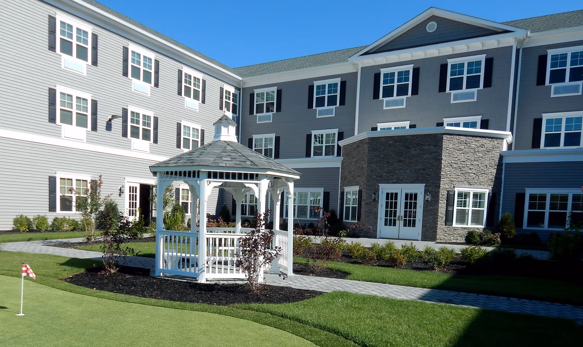 Exterior view of The Bristal Assisted Living at West Babylon with a gazebo courtyard