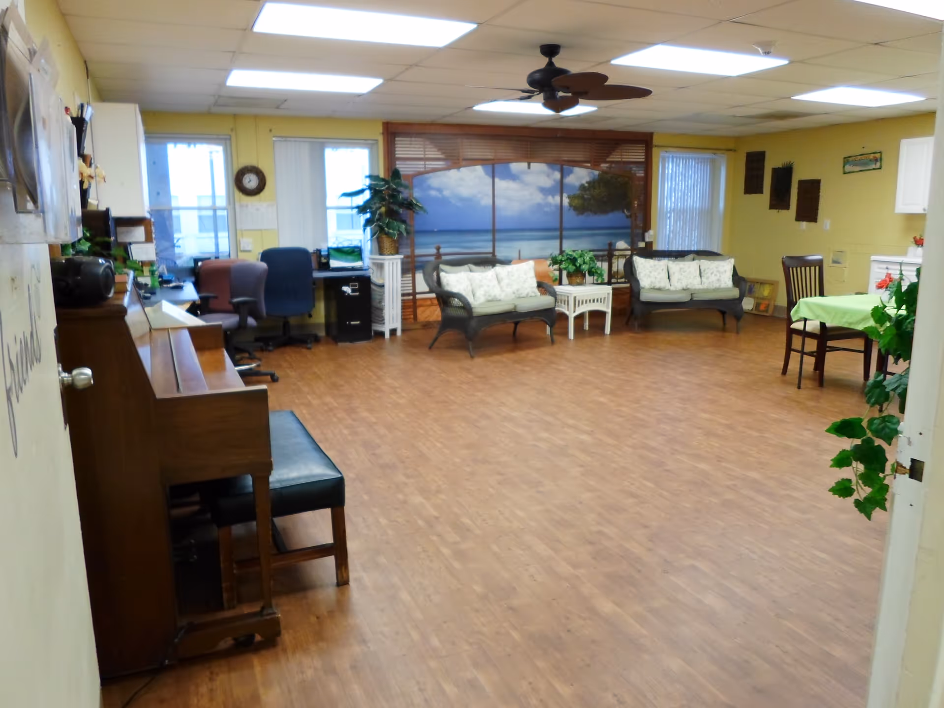 Spacious interior lounge at Ridge Valley Center with sofas, a piano, and tropical beach mural.