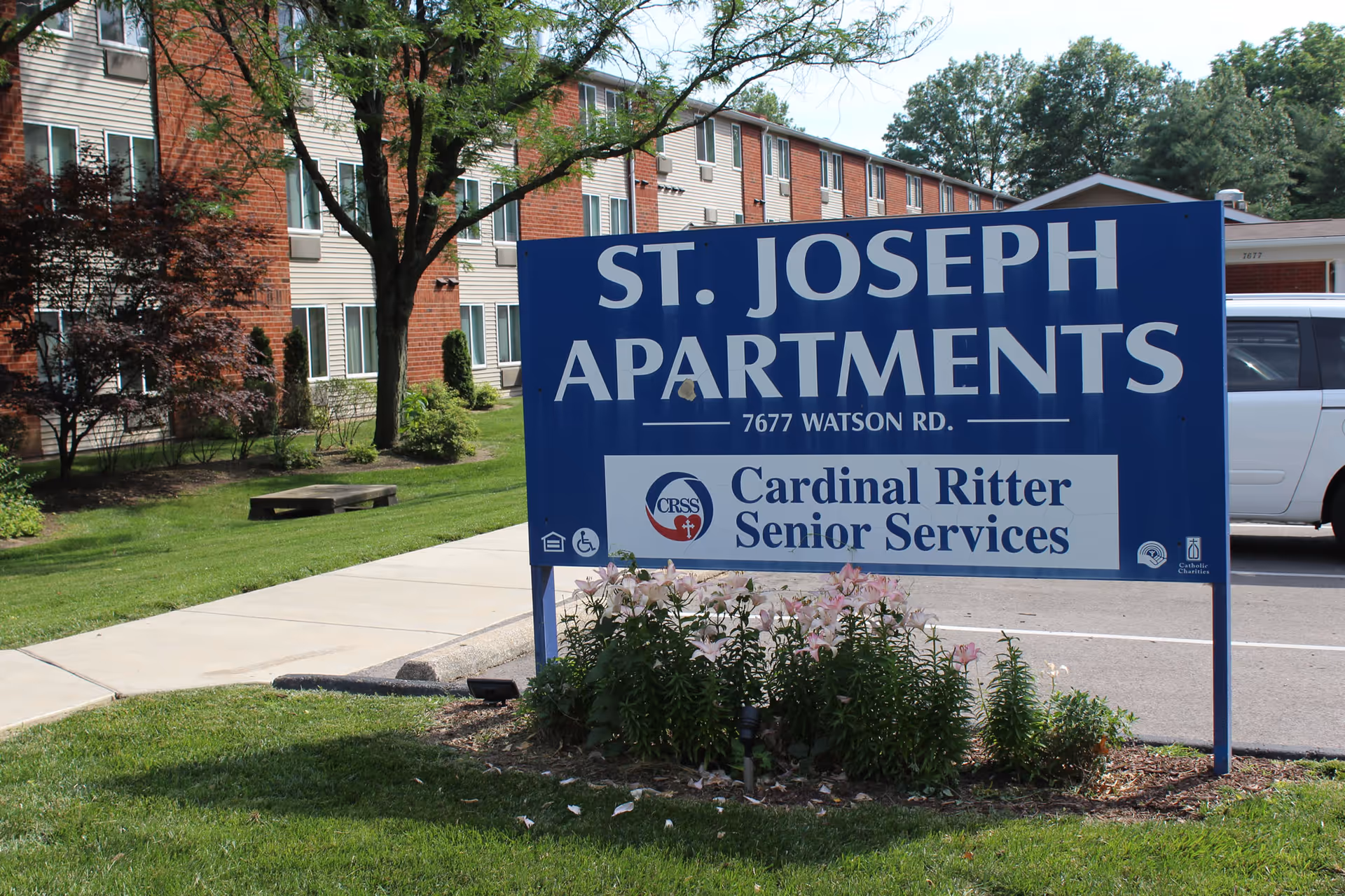 Exterior view of a senior apartments sign in front of a brick building and landscaping.