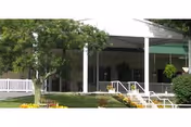 Front exterior of a senior care facility with white columns, green awning, and a ramp.