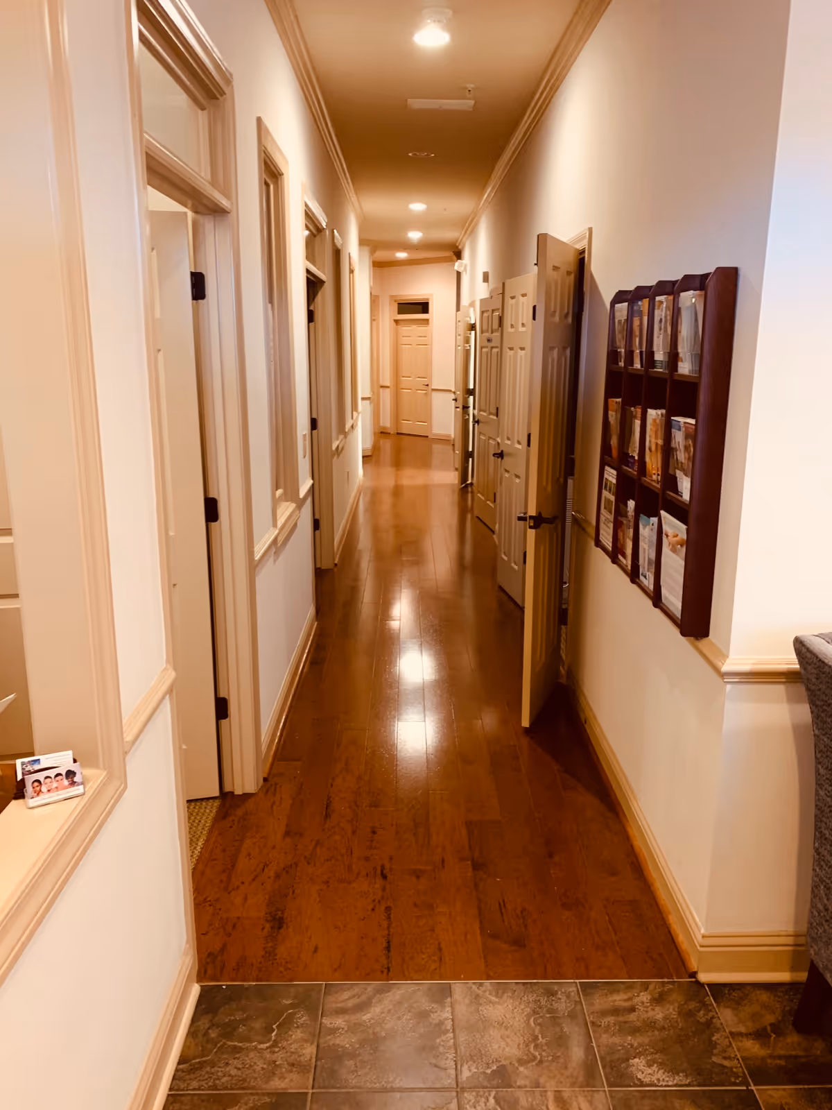 Long, well-lit hallway with wooden floors and closed doors on both sides.