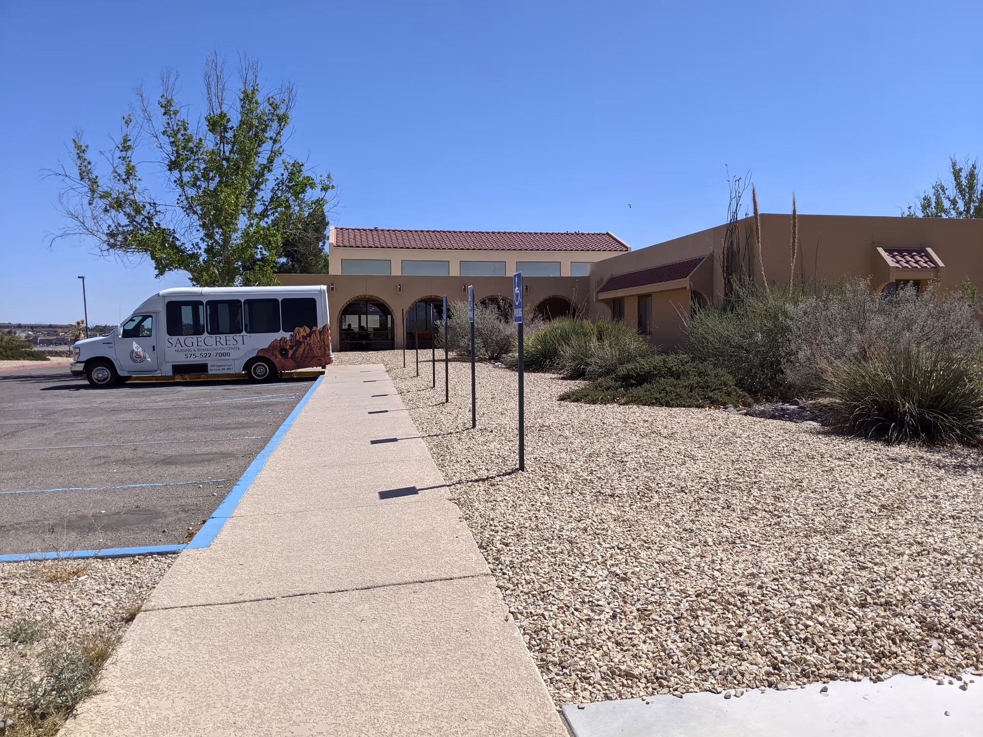 Exterior view of Calibre Post Acute facility with a parked bus and desert landscaping.