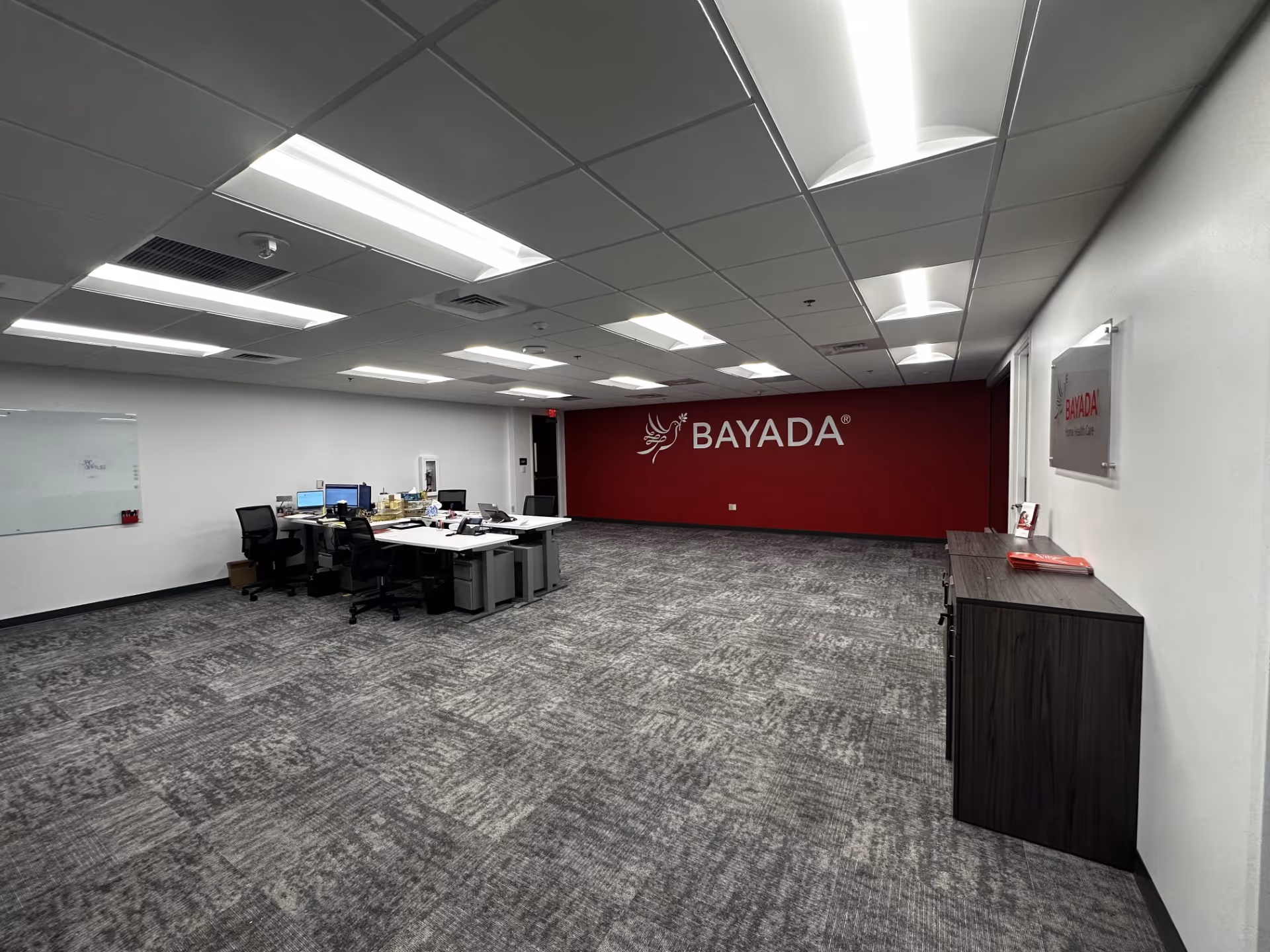 Open office area with BAYADA logo on a red wall and workstation desks