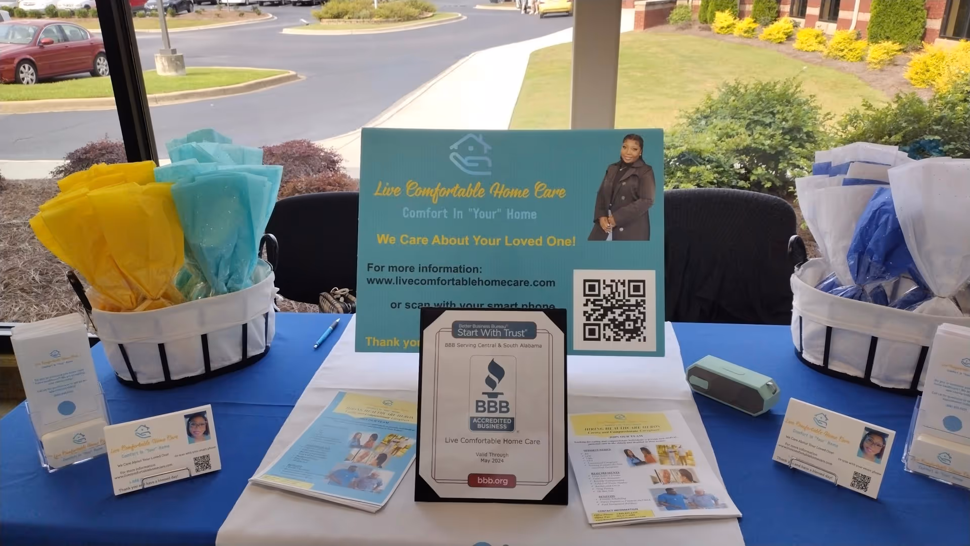 Promotional display on a blue-draped table with brochures and a Live Comfortable Home Care sign.
