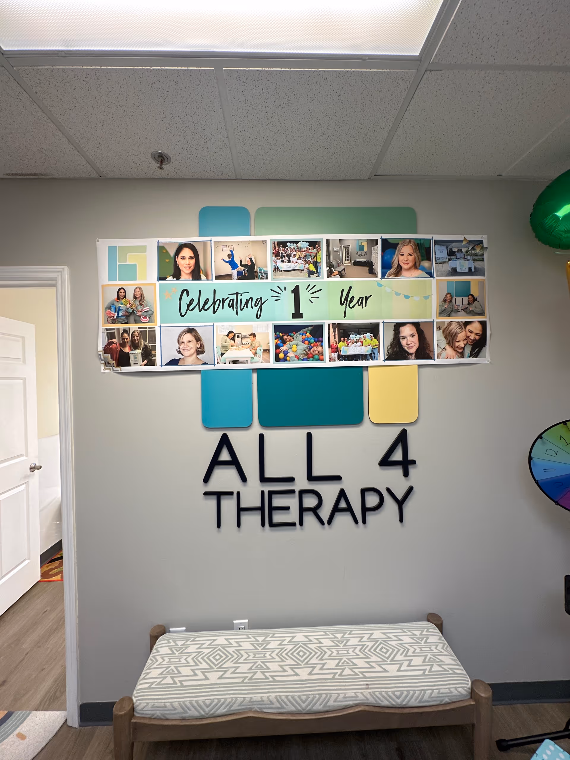 Interior wall with All 4 Therapy sign, photo collage, and bench seating.