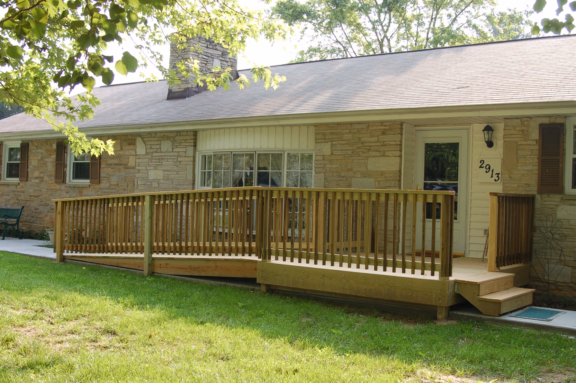 Greenway Manor, LLC entrance: a single-story stone building with a wooden ramp and steps.