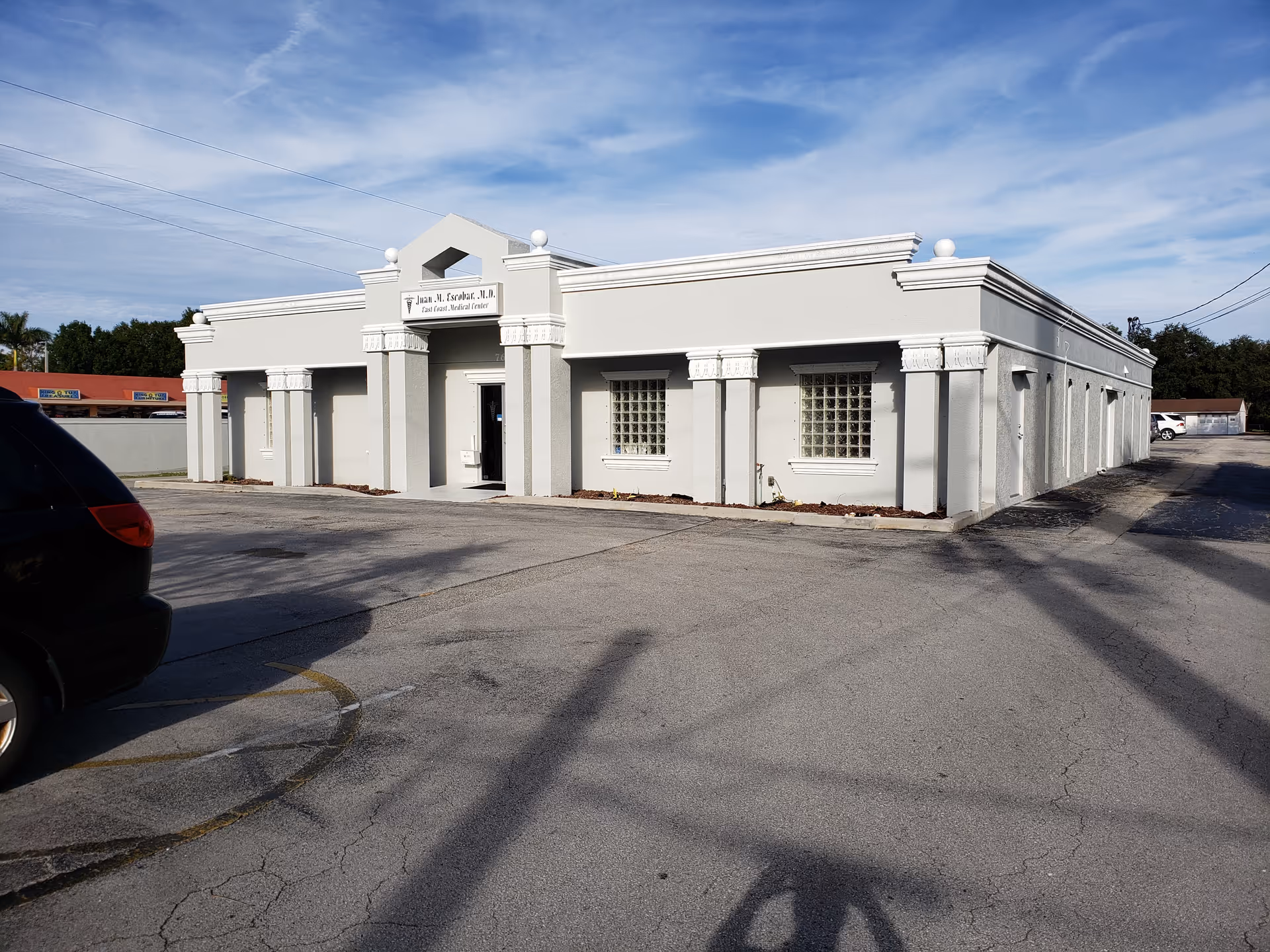 White, columned building exterior with a parking lot and blue sky