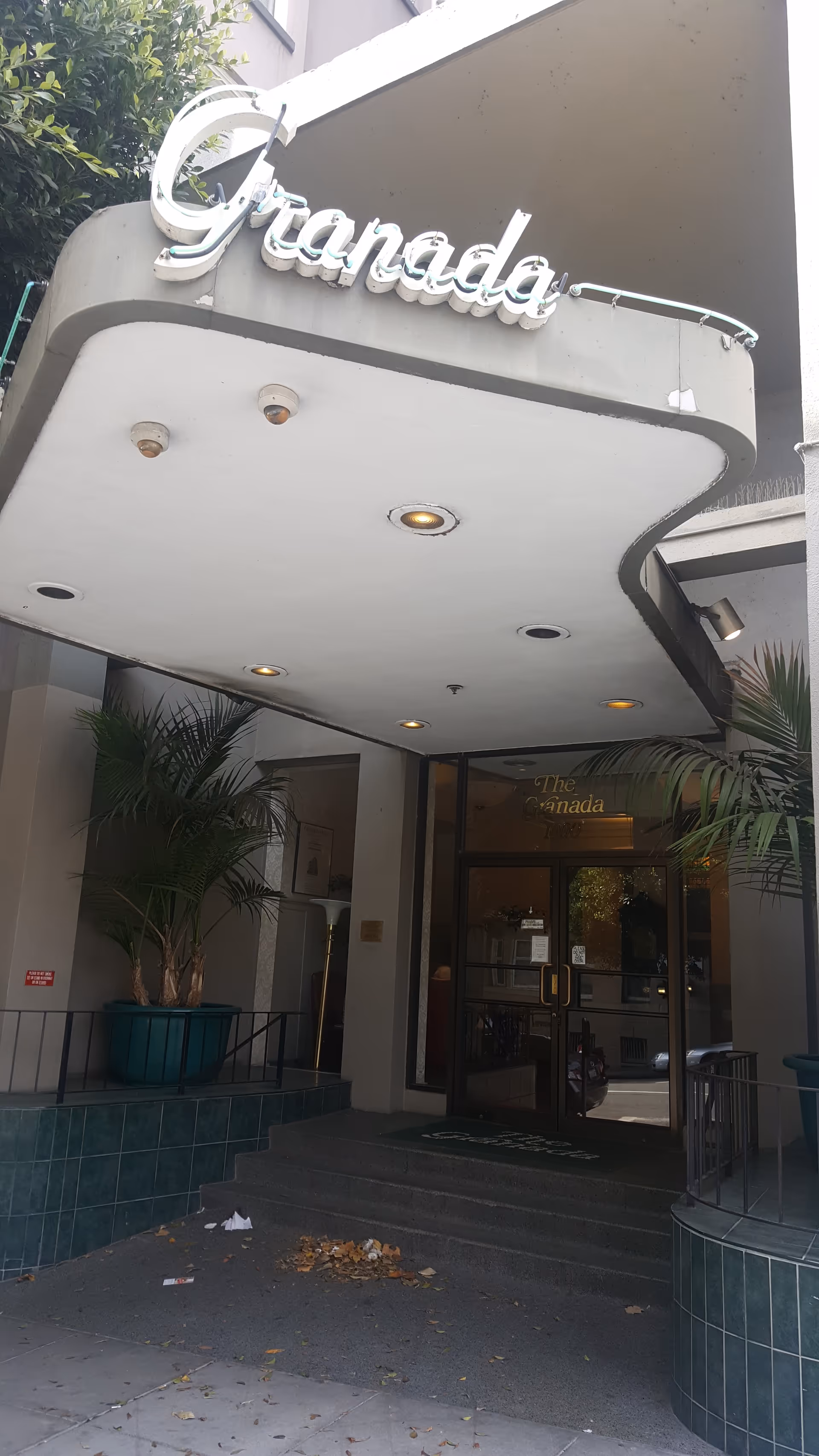 Exterior view of The Granada entrance with a curved canopy and glass doors.