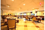 Spacious dining room with multiple tables and chairs under warm lighting.