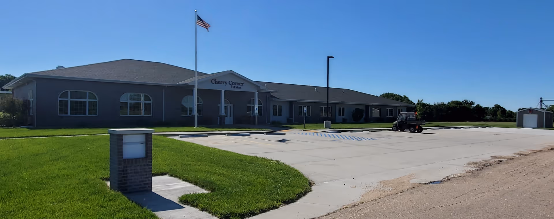 Exterior view of Cherry Corner Estates senior living facility with parking lot and flagpole.