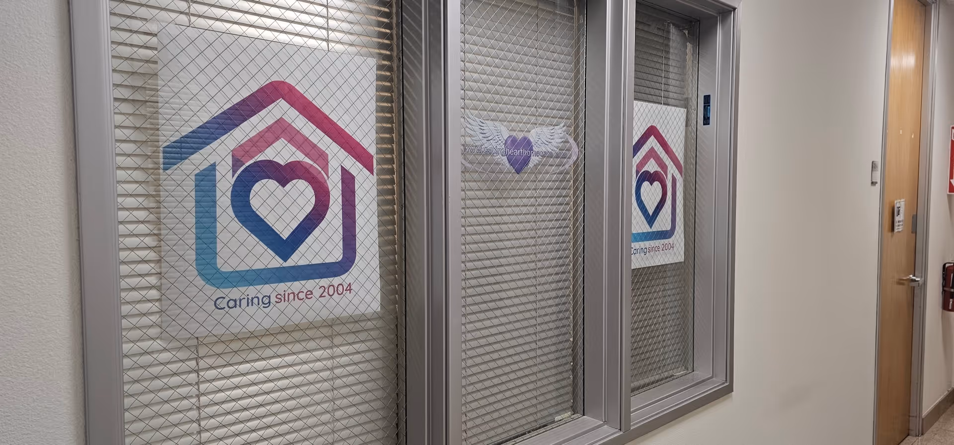 Interior hallway with windowed panels displaying Caring Heart Home Care logos.