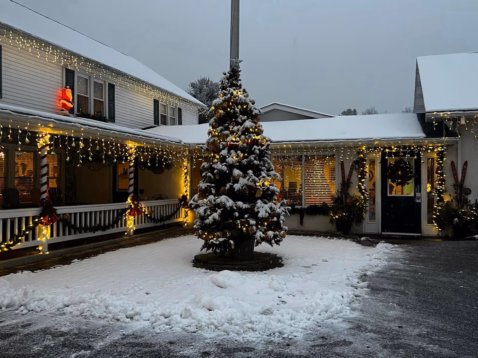 Snowy courtyard of Getz Personal Care Home with festive lights and a central decorated tree.