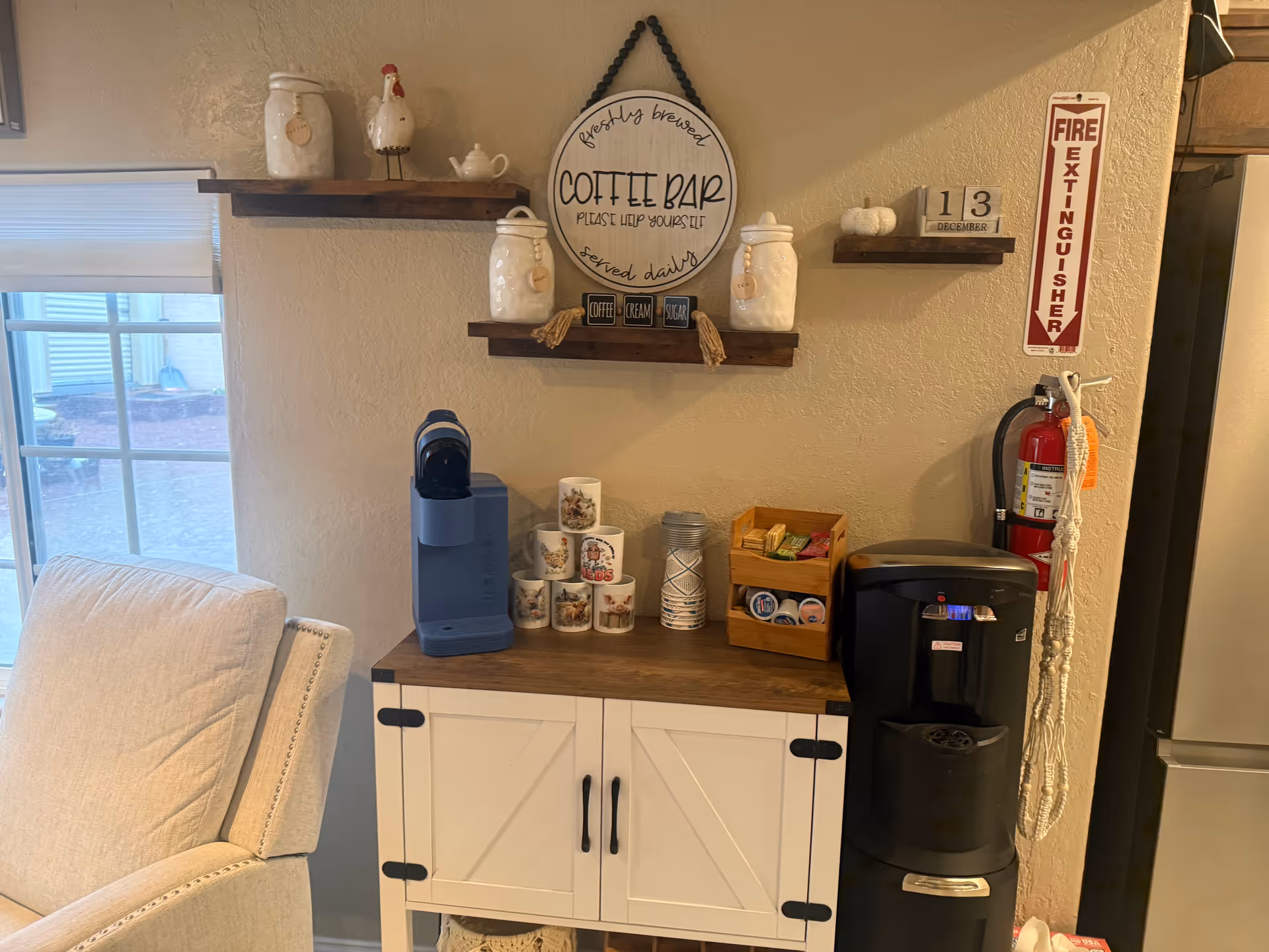 Interior coffee bar setup with mugs, jars, and a beverage station on a wooden counter.