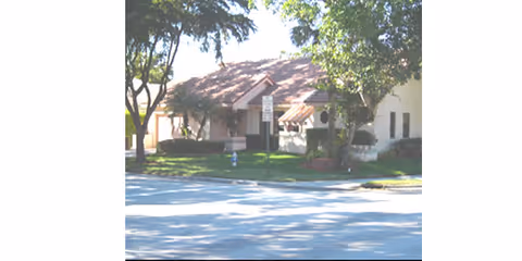 Exterior view of The Gardens at Coral Springs showing a building and surrounding trees.