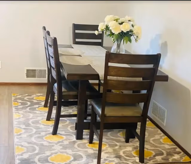 Dark wood dining table with chairs and vase of white flowers in dining room