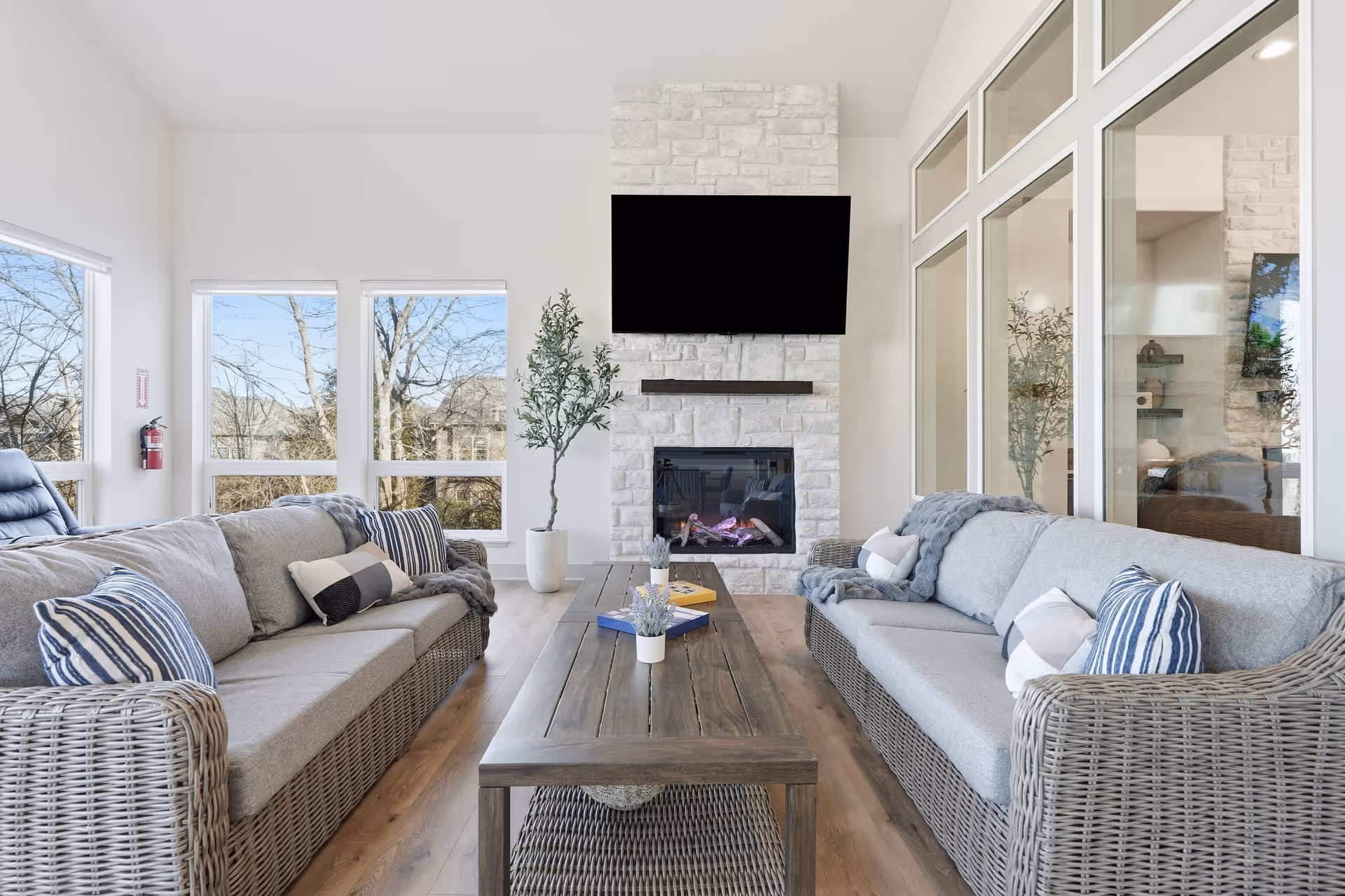 Bright, modern living room in a senior facility with a stone fireplace and large windows.