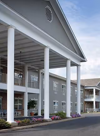 Exterior view of Lehigh Commons with white columns, covered entrance, and pastel-gray building.