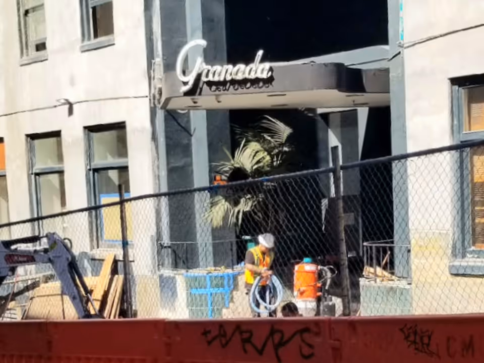 The Granada building entrance with a construction site and a worker nearby.