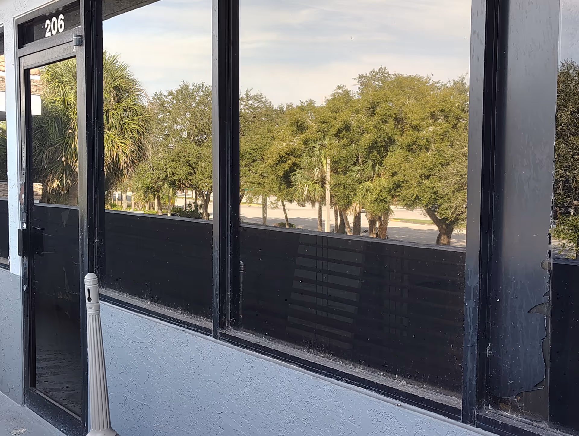 Exterior view of a facility entrance with glass doors and trees outside.
