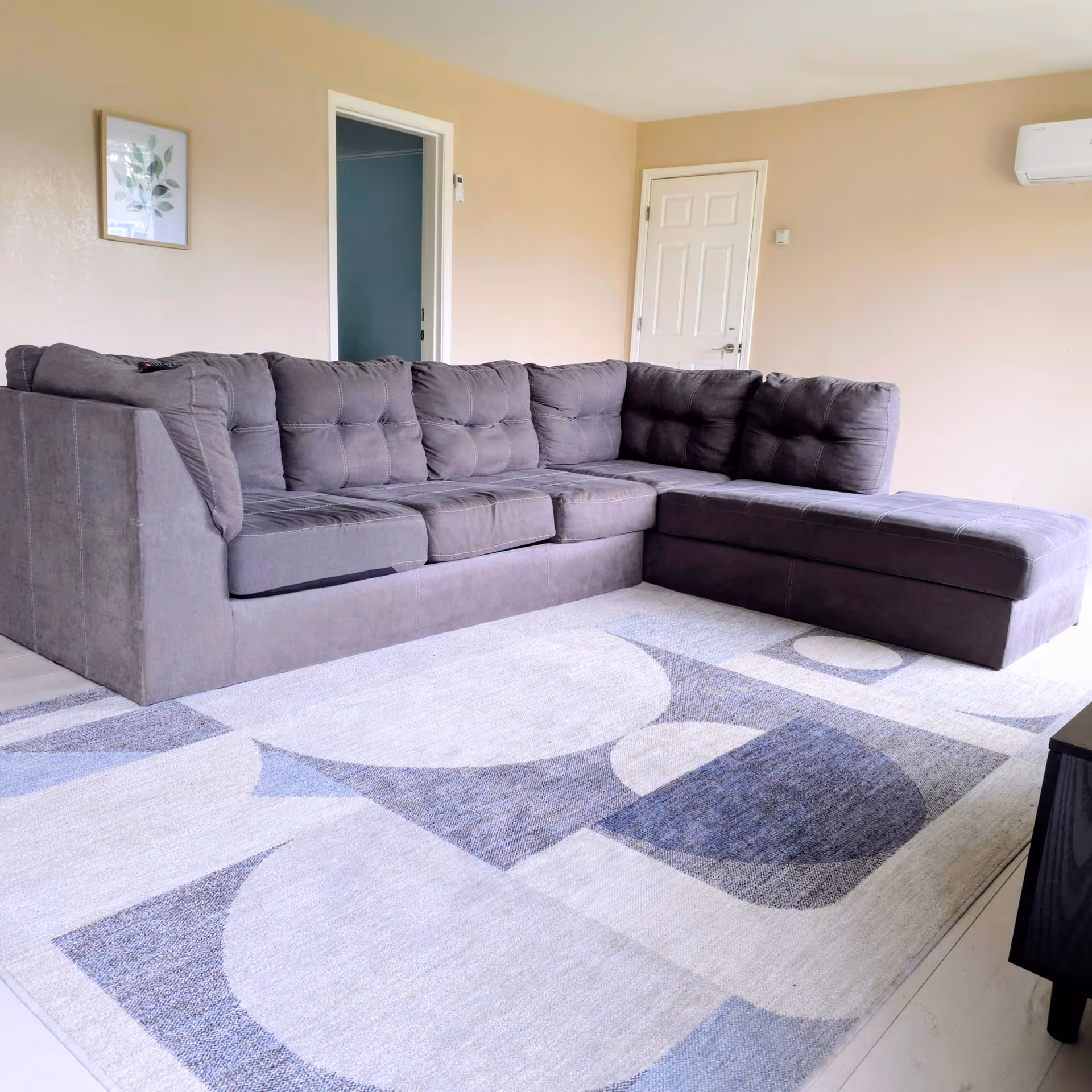 A spacious living room with a large gray sectional sofa and patterned area rug.
