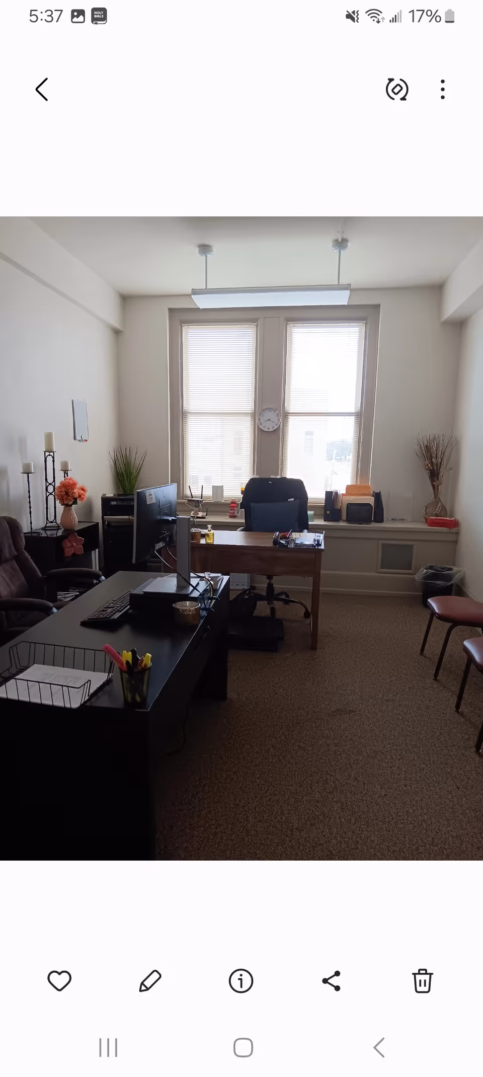 Small office inside a senior facility featuring desk, computer, plants, and blinds.