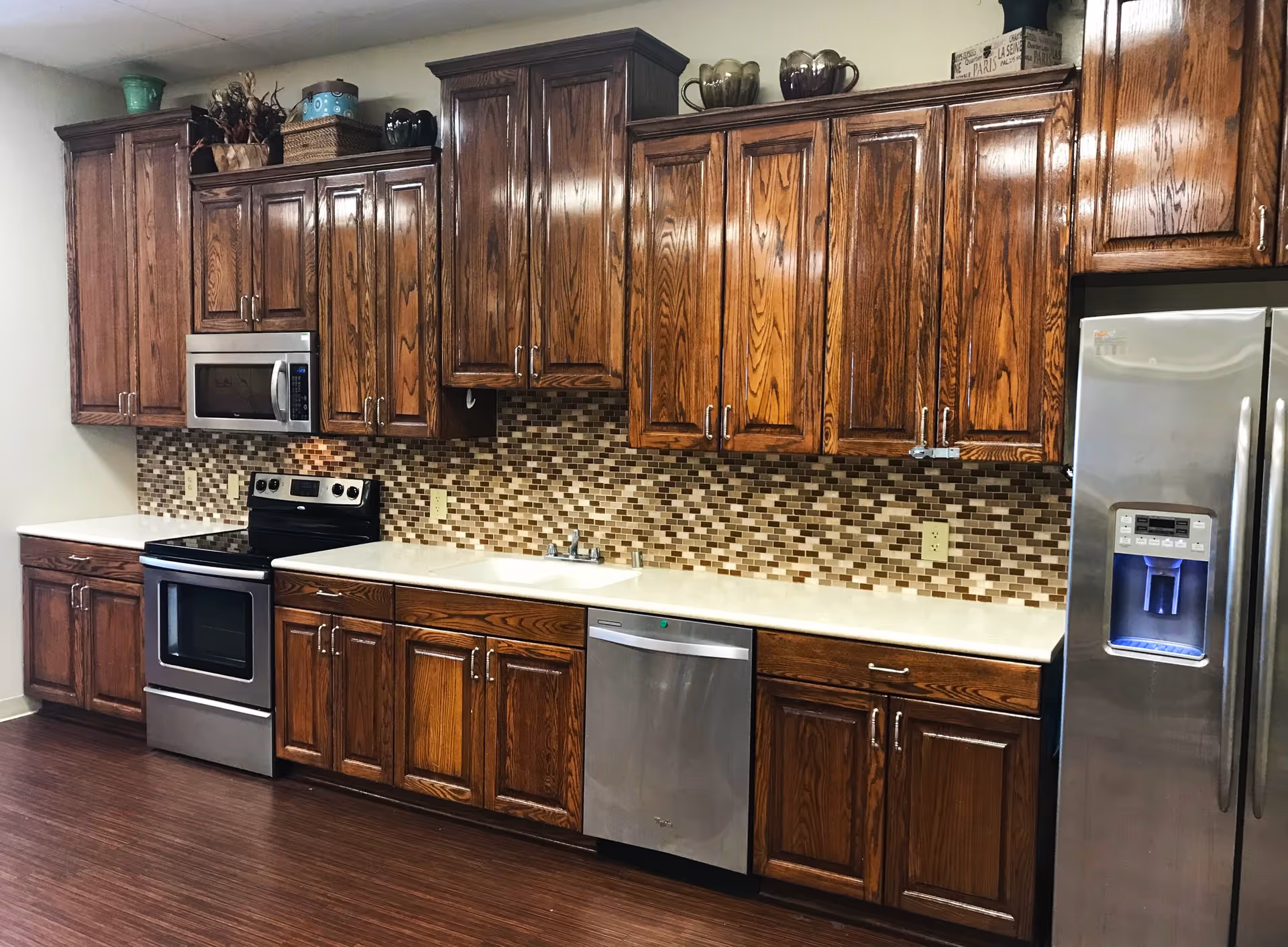 Kitchen with dark wood cabinets, stainless steel appliances, a mosaic tile backsplash, and light countertops.