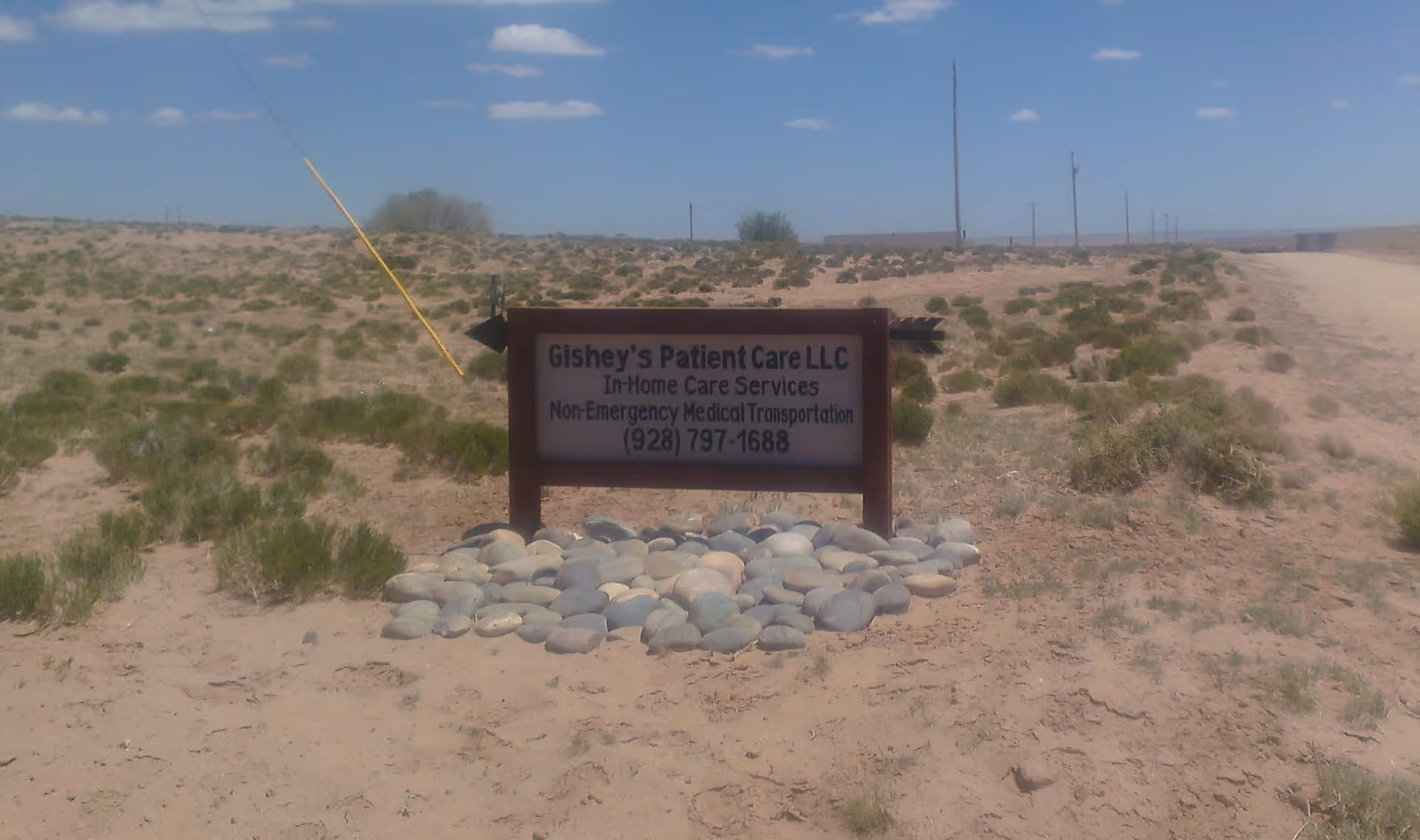 Desert landscape with Gishey's Patient Care LLC sign surrounded by rocks