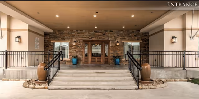 Front entrance of La Fontaine Memory Care with stone facade, steps, and planters.
