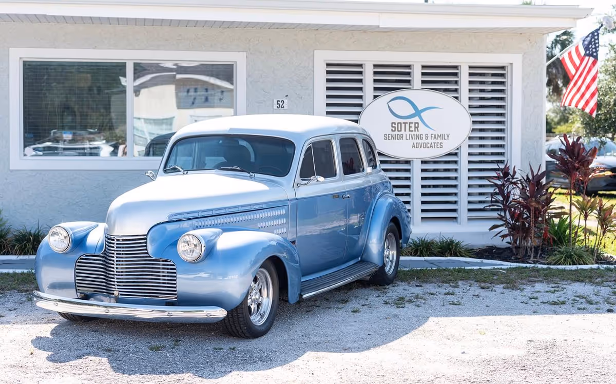A vintage blue car parked outside the Soter Senior Living & Family Advocates facility.